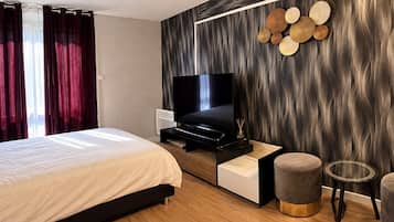 Ein modernes Schlafzimmer mit einem Bett, einem Fernseher, einem Nachttisch und einer Wanddekoration.