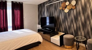 A modern bedroom with a bed, a TV, a bedside table, and a wall-mounted decorative item.