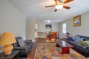A living room with a ceiling fan, a sofa, a coffee table, and a patterned rug. - 7 Mi to Mall of Georgia: Fire Pit & Yard (Buford)