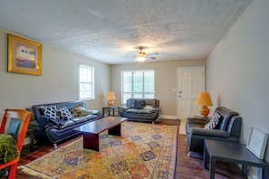 A living room with two sofas, a coffee table, a rug, and a ceiling fan.