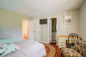 Un dormitorio con cama, una silla, cómoda y espejo.