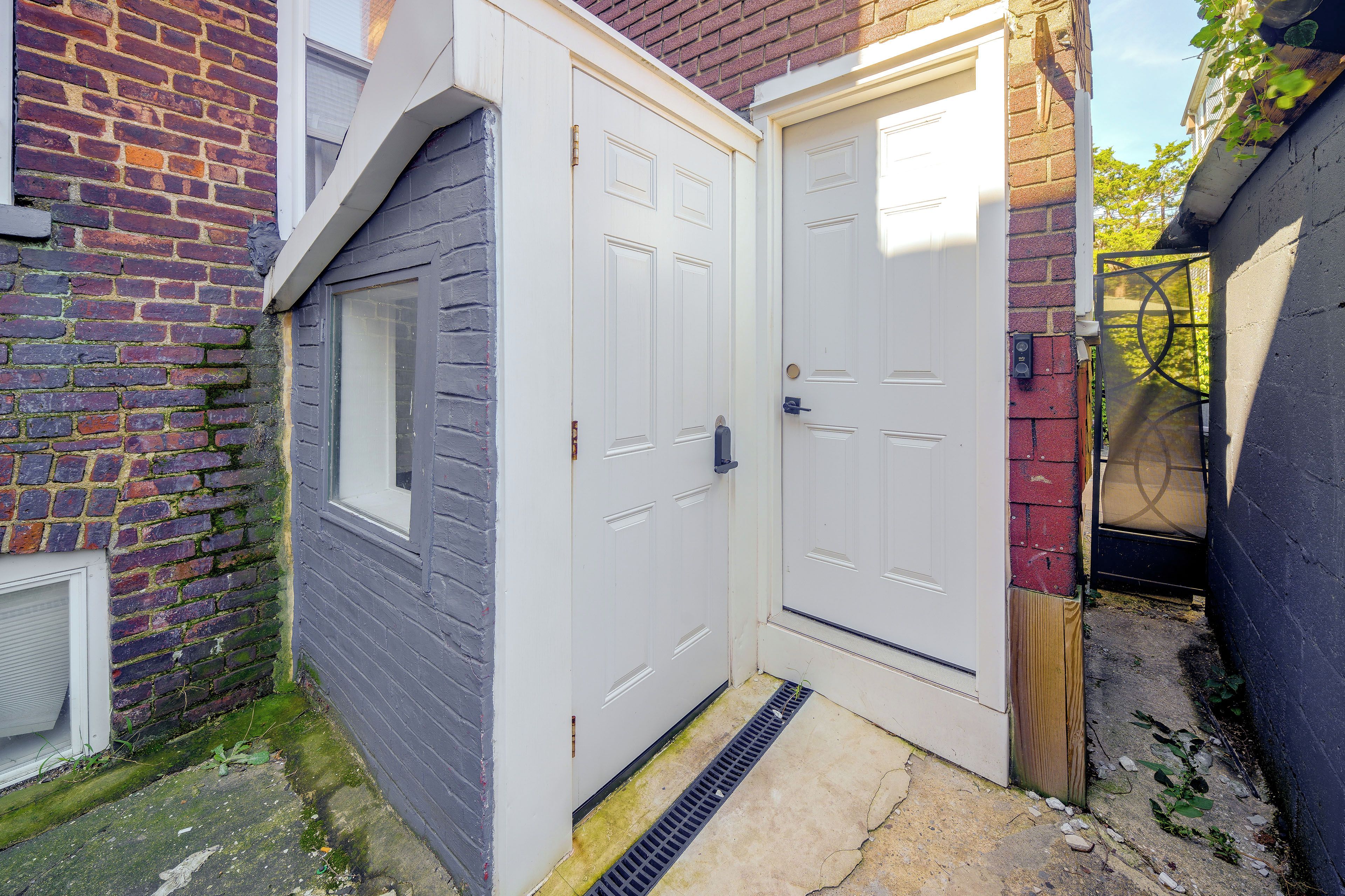 A white door with a window, a brick wall, and a metal gate.