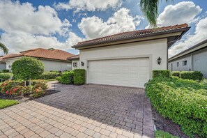 A residential property with a paved driveway, a garage, and well-maintained landscaping. - Tee Times + Poolside Vibes! Extended Naples Escape (Naples)