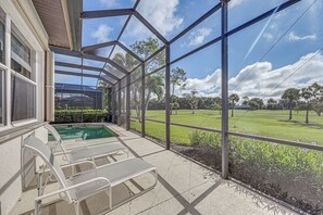 Un espace extérieur abrité comprenant une piscine, des chaises longues et une vue sur un terrain de golf.