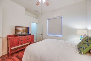 A bedroom with a bed, a TV on a wooden dresser, a window with blinds, and a ceiling fan. - Tee Times + Poolside Vibes! Extended Naples Escape (Naples)