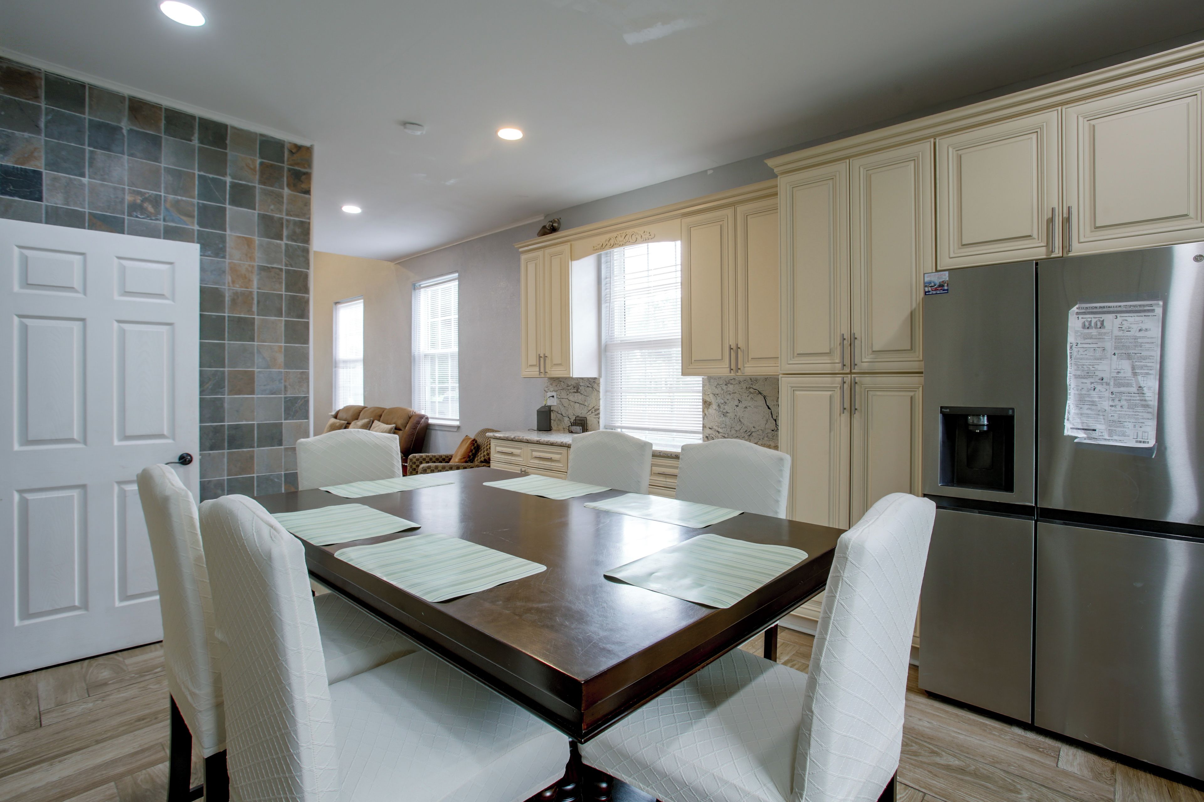 Una cocina moderna con una mesa de comedor, sillas y un refrigerador de acero inoxidable.