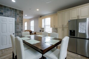 A modern kitchen with a dining table, chairs, and a stainless steel refrigerator.