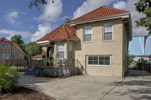 A two-story house with a red-tiled roof, a front porch with a bench, and a small garden area. - 4 Mi to Bourbon St & Superdome! Spacious Home (New Orleans)