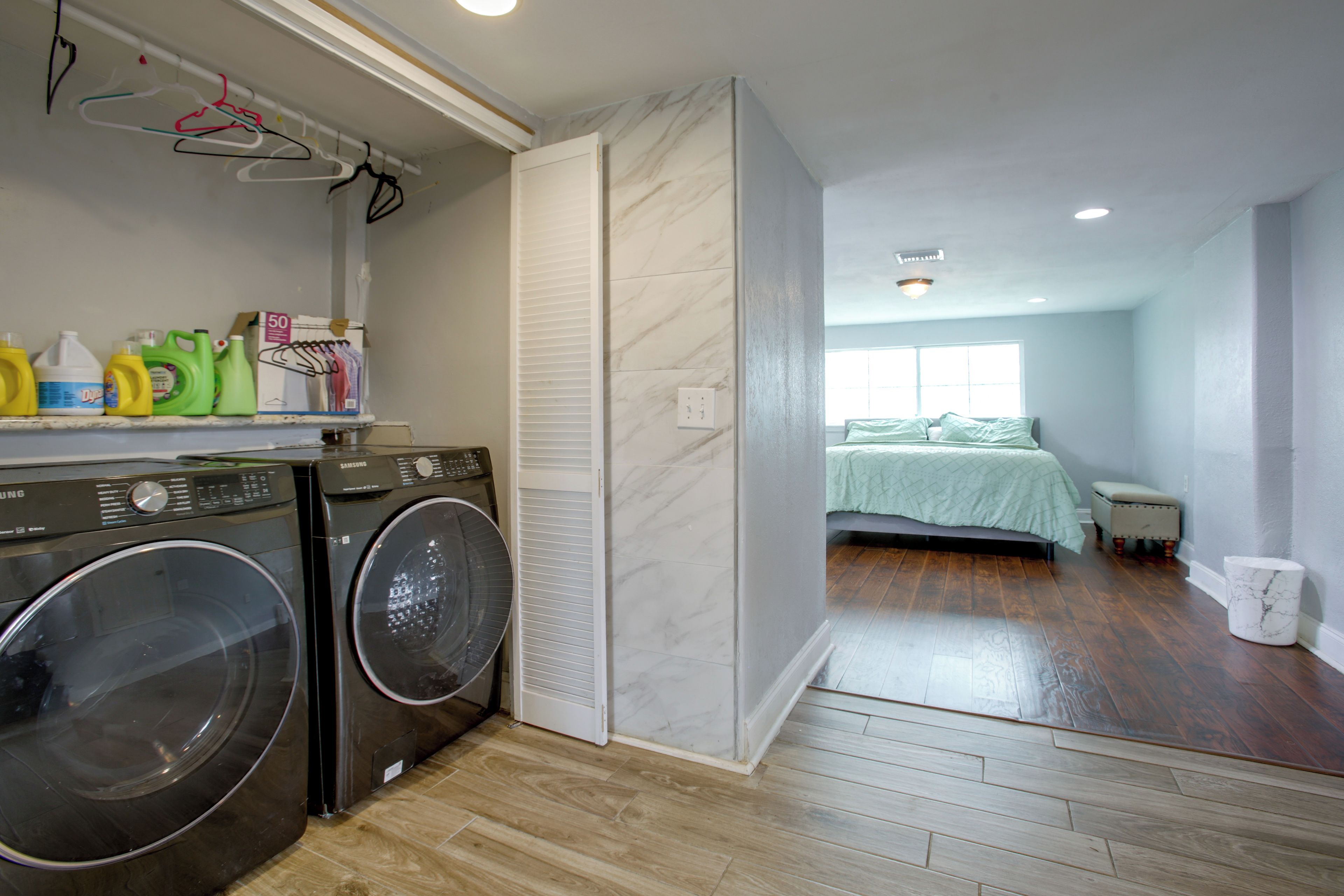 A laundry room with two washing machines, a drying rack, and laundry supplies.