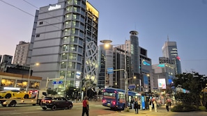 A modern urban street scene with high-rise buildings, including a hotel with a distinctive geometric facade. - [5 Min to DDP & APM] 2BR · 2 Queen Beds · 4 Guests (Seoul)