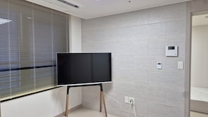 A room with a flat-screen TV on an easel, a thermostat, and a power outlet on the wall. - [5 Min to DDP & APM] 2BR · 2 Queen Beds · 4 Guests (Seoul)