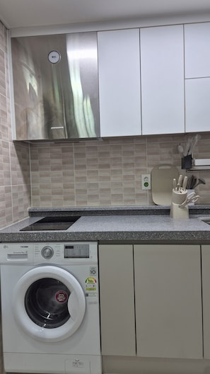 A compact kitchen with a built-in washing machine, a stainless steel range hood, and a tiled backsplash. - [5 Min to DDP & APM] 2BR · 2 Queen Beds · 4 Guests (Seoul)