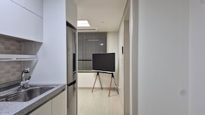 A narrow kitchen with a sink, a window with blinds, and a blackboard on a stand. - [5 Min to DDP & APM] 2BR · 2 Queen Beds · 4 Guests (Seoul)