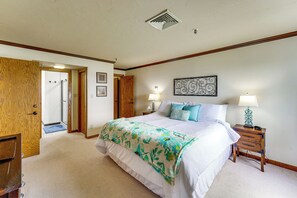 A bedroom with a large bed, two bedside lamps, a wall clock, and a door leading to another room. - Grand Lake Golf Course Getaway: Stunning Views! (Afton)