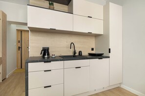 Eine moderne Küche mit weißen Schränken, einer schwarzen Arbeitsplatte und einer eingebauten Spüle.