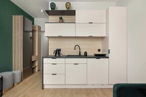 Eine moderne Küche mit weißen Schränken, einer schwarzen Arbeitsplatte und einer Holzrückwand.