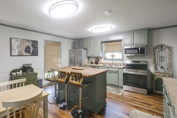 A kitchen with a central island, bar stools, a refrigerator, a microwave, an oven, and a dining table with chairs.
