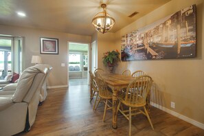 A dining area with a wooden table and chairs, a chandelier, and a cityscape painting on the wall. - Game Room, Private Dock! Grand Lake Group Retreat (Grove)