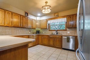 A kitchen with wooden cabinets, a dishwasher, and a refrigerator. - Game Room, Private Dock! Grand Lake Group Retreat (Grove)