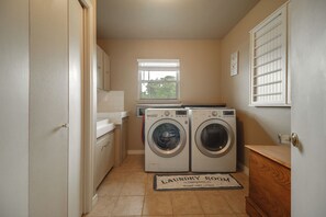 A laundry room with two front-loading washing machines, a window, and a door leading to another room. - Game Room, Private Dock! Grand Lake Group Retreat (Grove)