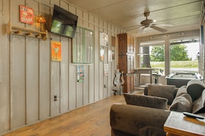 A room with a wooden floor, a ceiling fan, a television, and a view of the outdoors. - Game Room, Private Dock! Grand Lake Group Retreat (Grove)