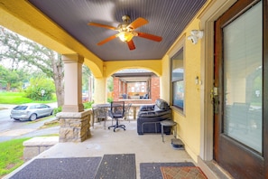 A covered outdoor seating area with a ceiling fan, a stone column, and a brick building in the background. - Kansas City Rental Near Union Station & Hospitals (Kansas City)
