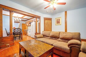 A living room with a wooden table, a sofa, and a ceiling fan. - Kansas City Rental Near Union Station & Hospitals (Kansas City)