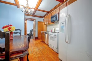A kitchen with wooden cabinets, a white refrigerator, a microwave, and a stove. - Kansas City Rental Near Union Station & Hospitals (Kansas City)