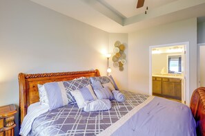 A bedroom with a large bed, a bedside table, a wall-mounted light, and a bathroom visible through an open door. - 1 Mi to Flanagan Park & Golf! Peaceful Home (Bennington)