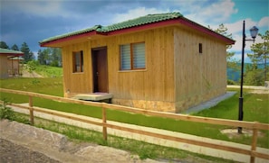Una cabaña de madera con techo rojo, una puerta y una ventana.