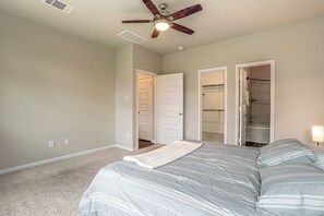 A bedroom with a bed, a ceiling fan, and two doors leading to a bathroom and closet. - Yard, Patio! Spacious Family Home By The Woodlands (Conroe)