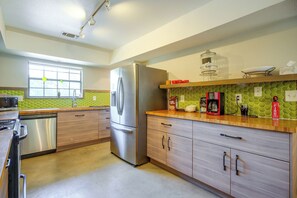 Eine moderne Küche mit einem Edelstahl-Kühlschrank, Holzschränken, einer Mikrowelle und einer Kaffeemaschine auf der Arbeitsplatte.