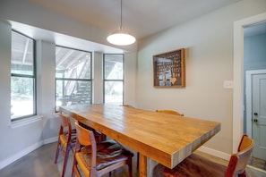 A dining area with a wooden table and chairs, large windows, and a pendant light. - 9 Mi to Six Flags! Wooded Retreat w/ Patio (San Antonio)