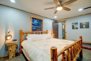 A bedroom with a wooden bed frame, a ceiling fan, a window with blinds, and a door. - 1/2 Mi to Marina! Modern Bull Shoals Lake Cabin (Bull Shoals)