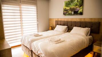 A double bed with a wooden headboard, two bedside tables, and a painting of a garden on the wall.