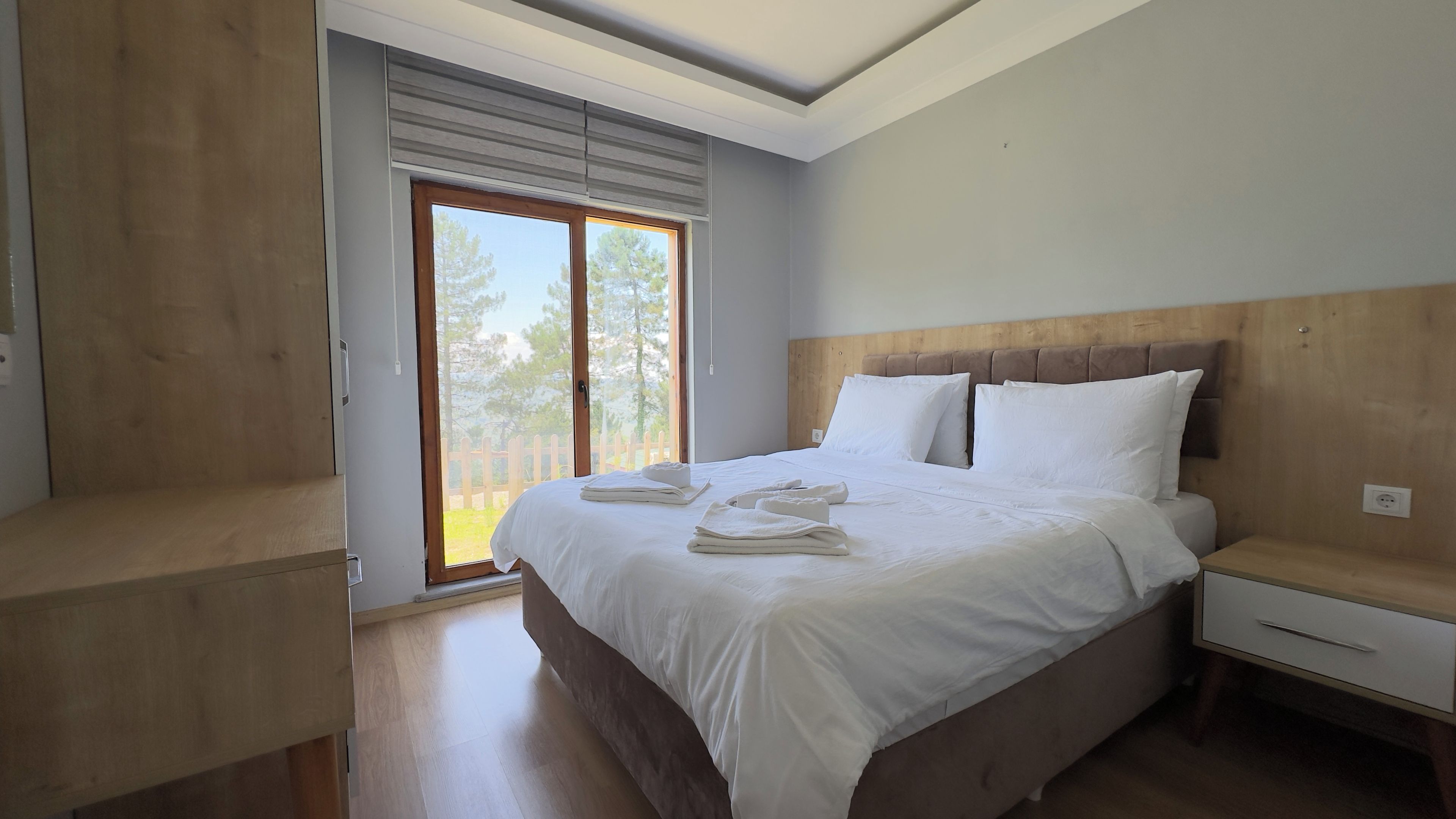 Un dormitorio con una cama grande, cabecero de madera, una mesita de noche y una ventana con persianas.