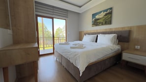 A bedroom with a large bed, a wooden headboard, a nightstand, and a painting on the wall. - Ultra-luxury villa for rent 00012 (İnkur)
