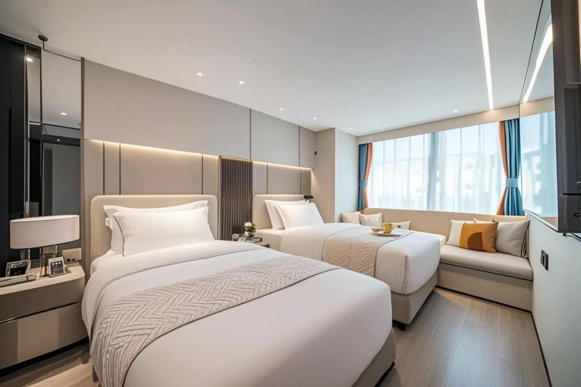 Habitación de hotel moderna con dos camas, un sofá, una mesita de noche y un ventanal con cortinas.