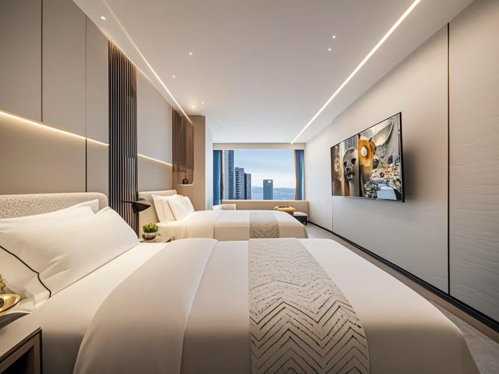 A modern hotel room with a large bed, a sofa, a city view, and a wall-mounted artwork.