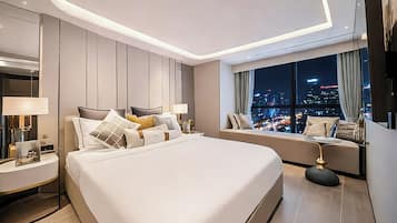 A modern hotel room with a large bed, bedside tables, a seating area with a view of the city at night.