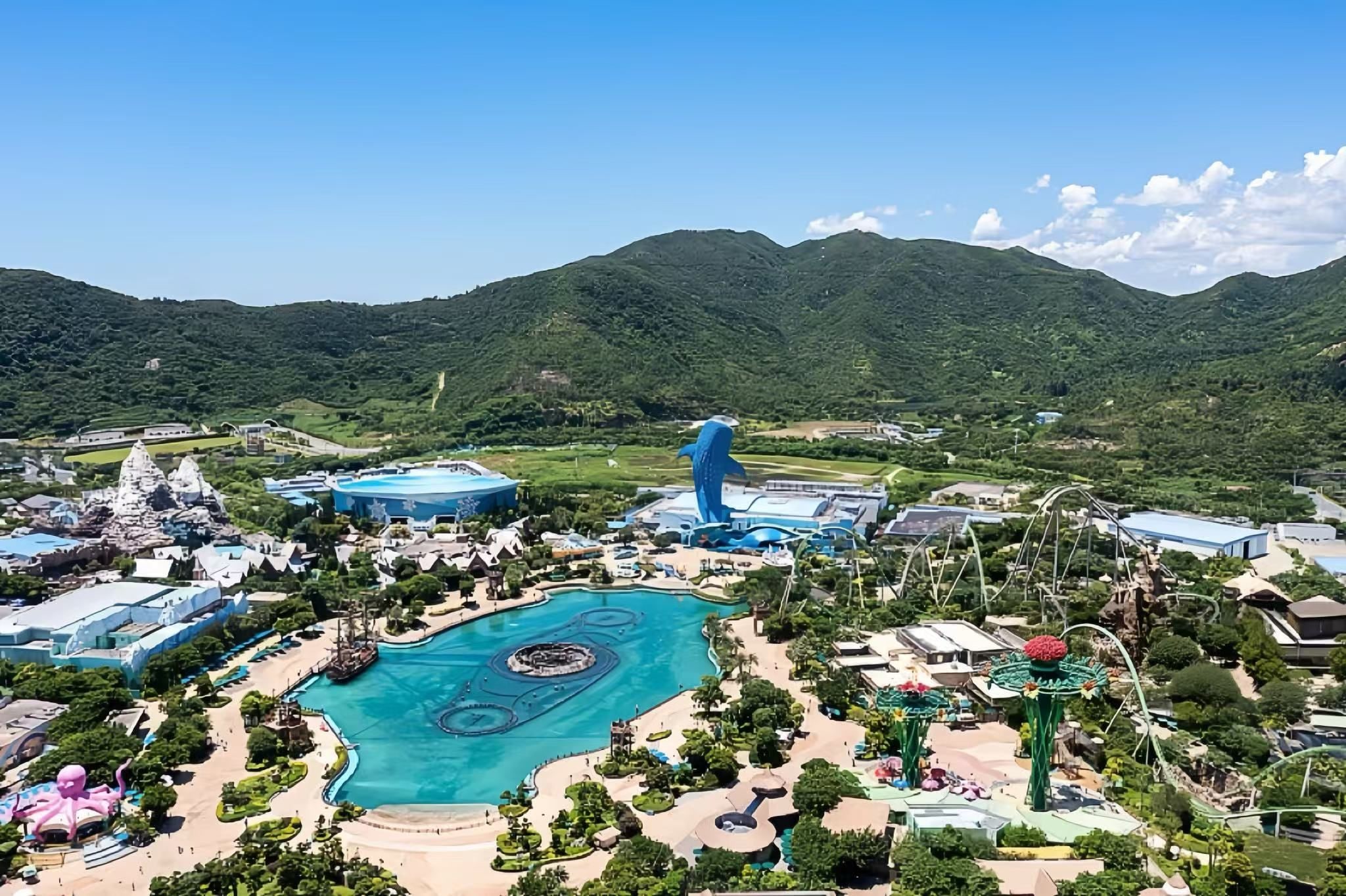 Parque temático con una amplia piscina central, diversas atracciones y edificios.