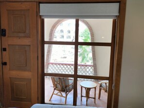 Ein Zimmer mit Holztür und Fenster mit Blick auf eine Terrasse mit Stühlen und einem Tisch.