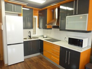A modern kitchen with a refrigerator, microwave, sink, and orange cabinets. - Charming 1-Bedroom Apartment near the beach in Roquetas de Mar, Spain (Roquetas de Mar)