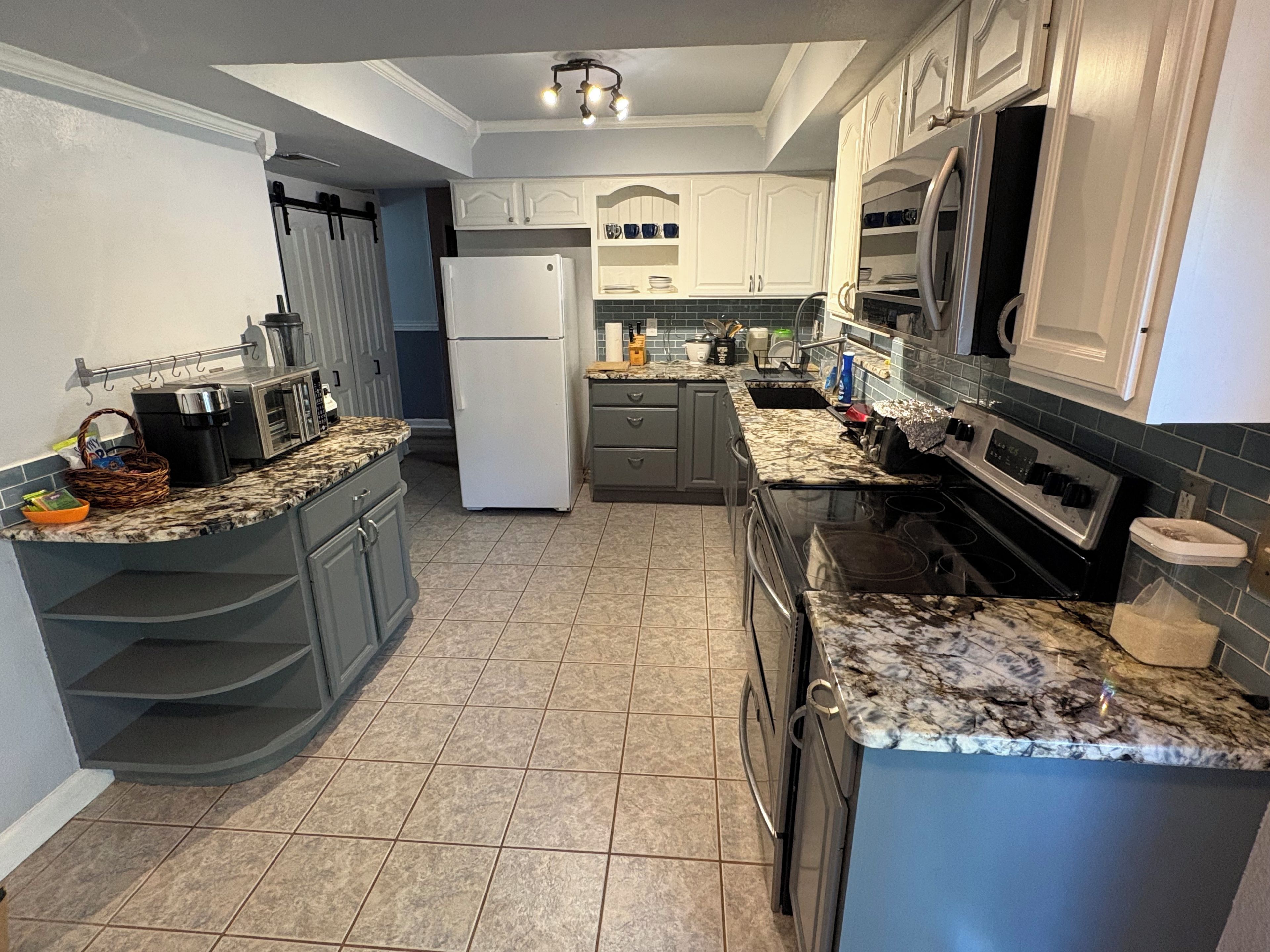 A kitchen with white cabinets, a refrigerator, a stove, and a microwave.
