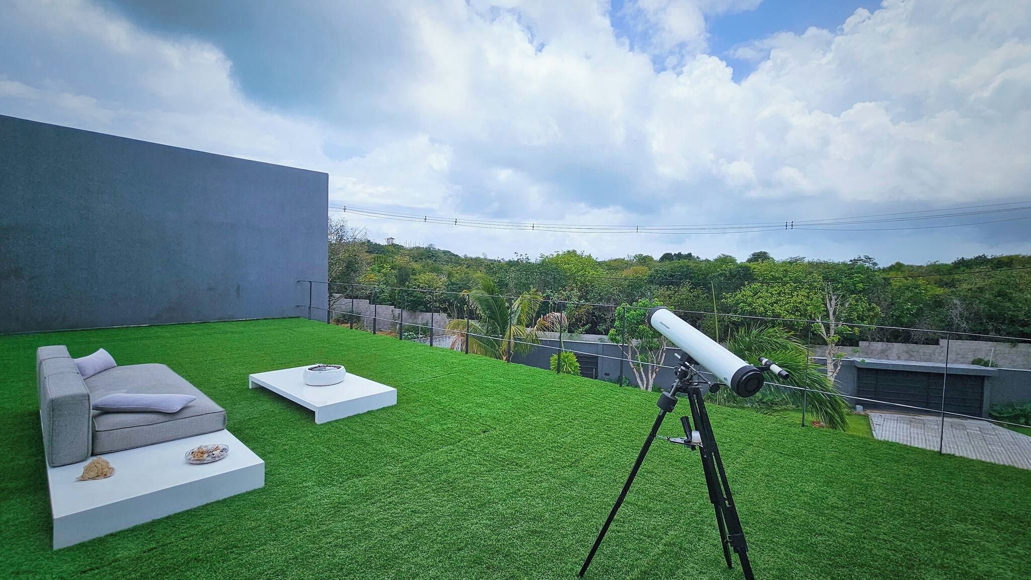 Une terrasse sur le toit équipée d’un télescope, d’un canapé et d’une table basse.