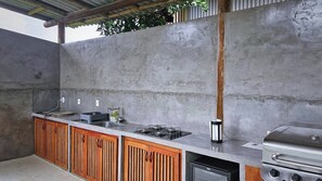 A kitchen with a built-in gas stove, a sink, and wooden cabinets. - Celia’s Beautiful House (Tibau do Sul)