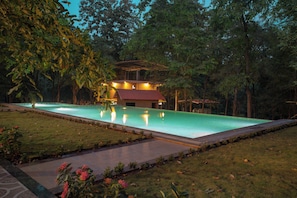 A swimming pool with a surrounding garden and a building with a red roof.