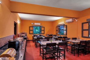 A restaurant with orange walls, black chairs, and a buffet area with food containers.