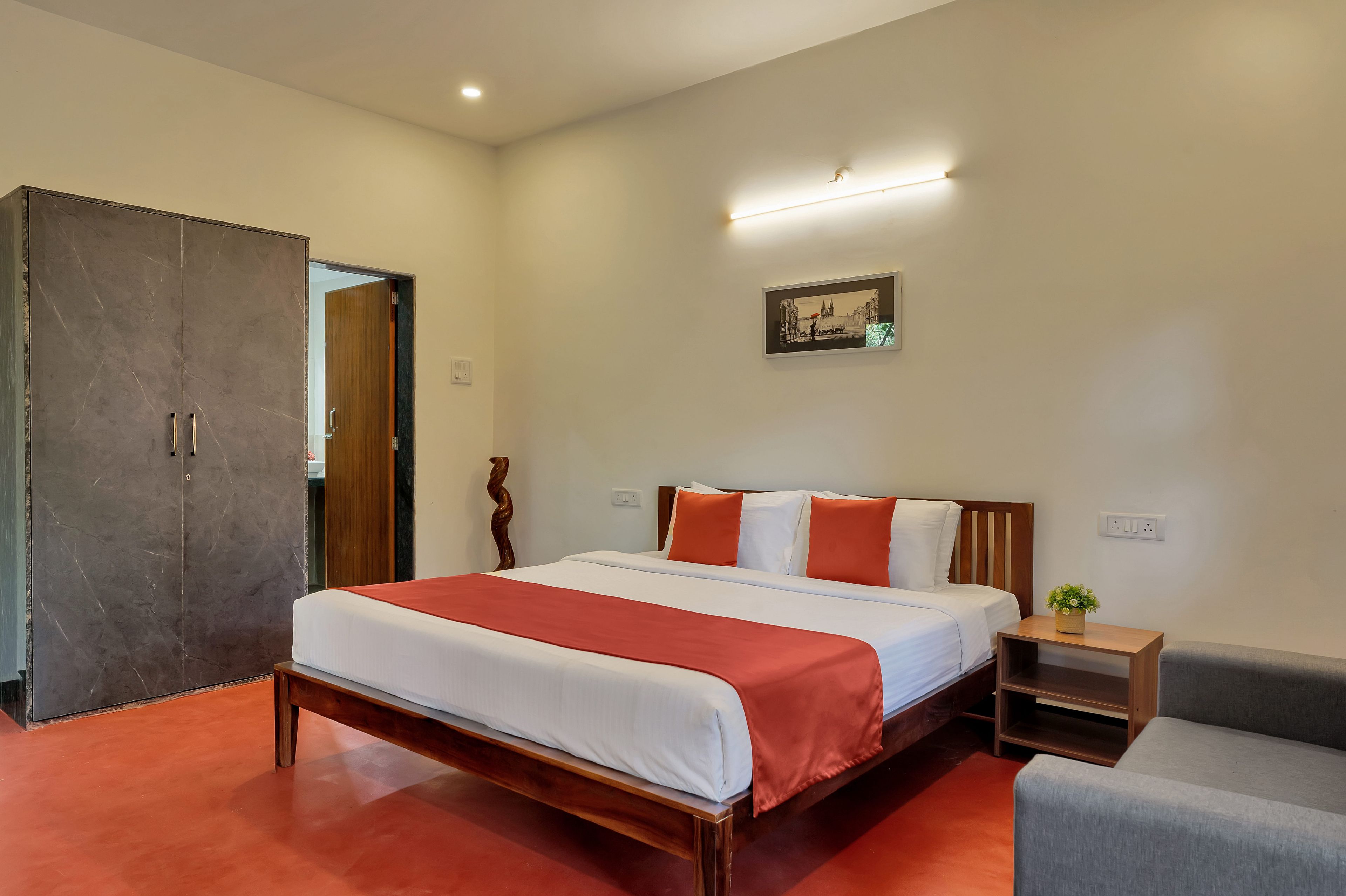 A hotel room with a wooden bed, a small bedside table, a chair, and a large wardrobe.