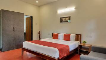 A hotel room with a wooden bed, a small bedside table, a chair, and a large wardrobe.